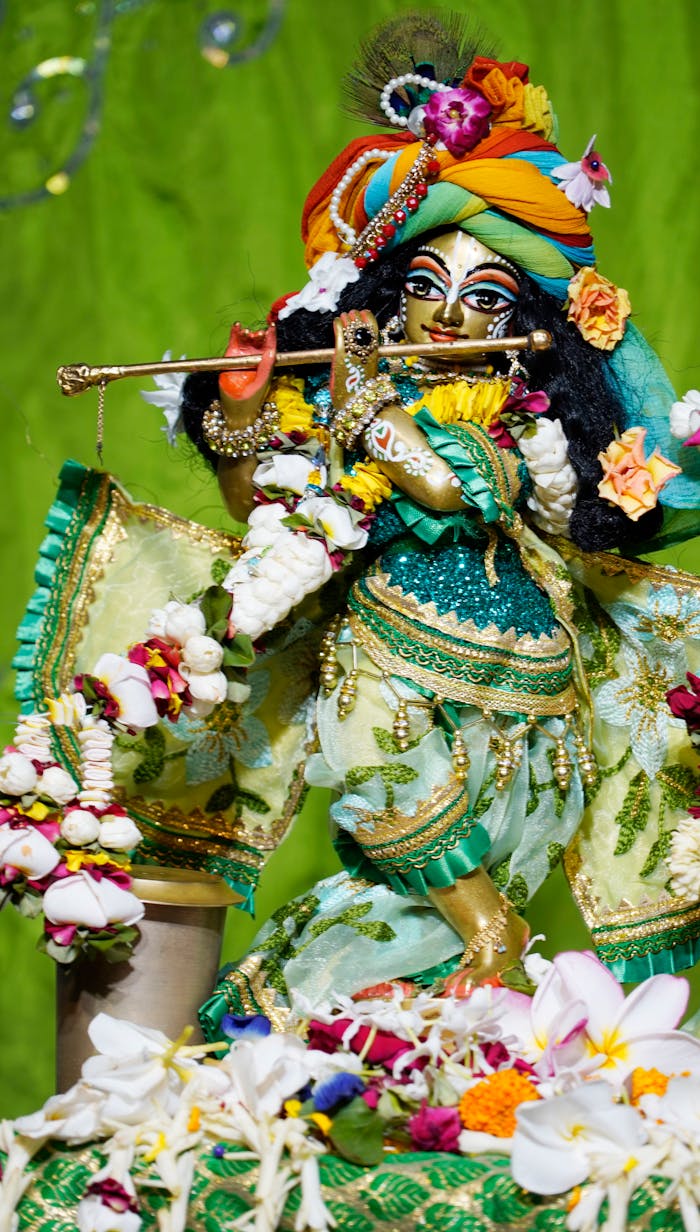 Offerings Vibrant Krishna statue adorned with flowers and traditional attire, captured in a ceremonial setting.