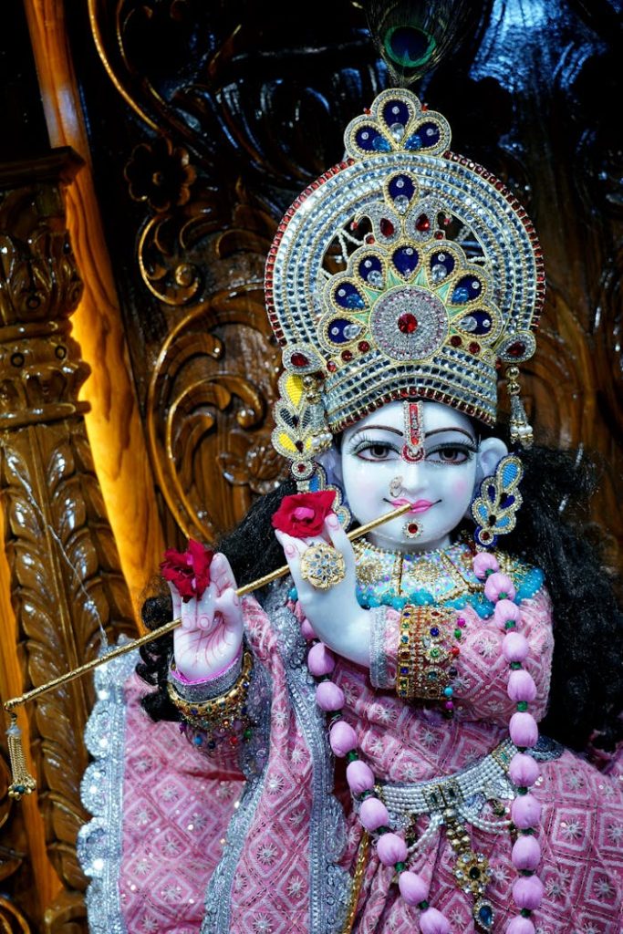 Mastering the First Impression: Your intriguing post title goes here Intricate statue of Krishna adorned in colorful attire, holding flute and roses, showcasing Hindu artistry.