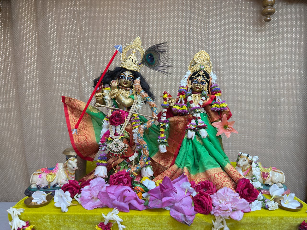 Home Vibrant statues of Hindu deities adorned with flowers, depicting a traditional ritual setup.